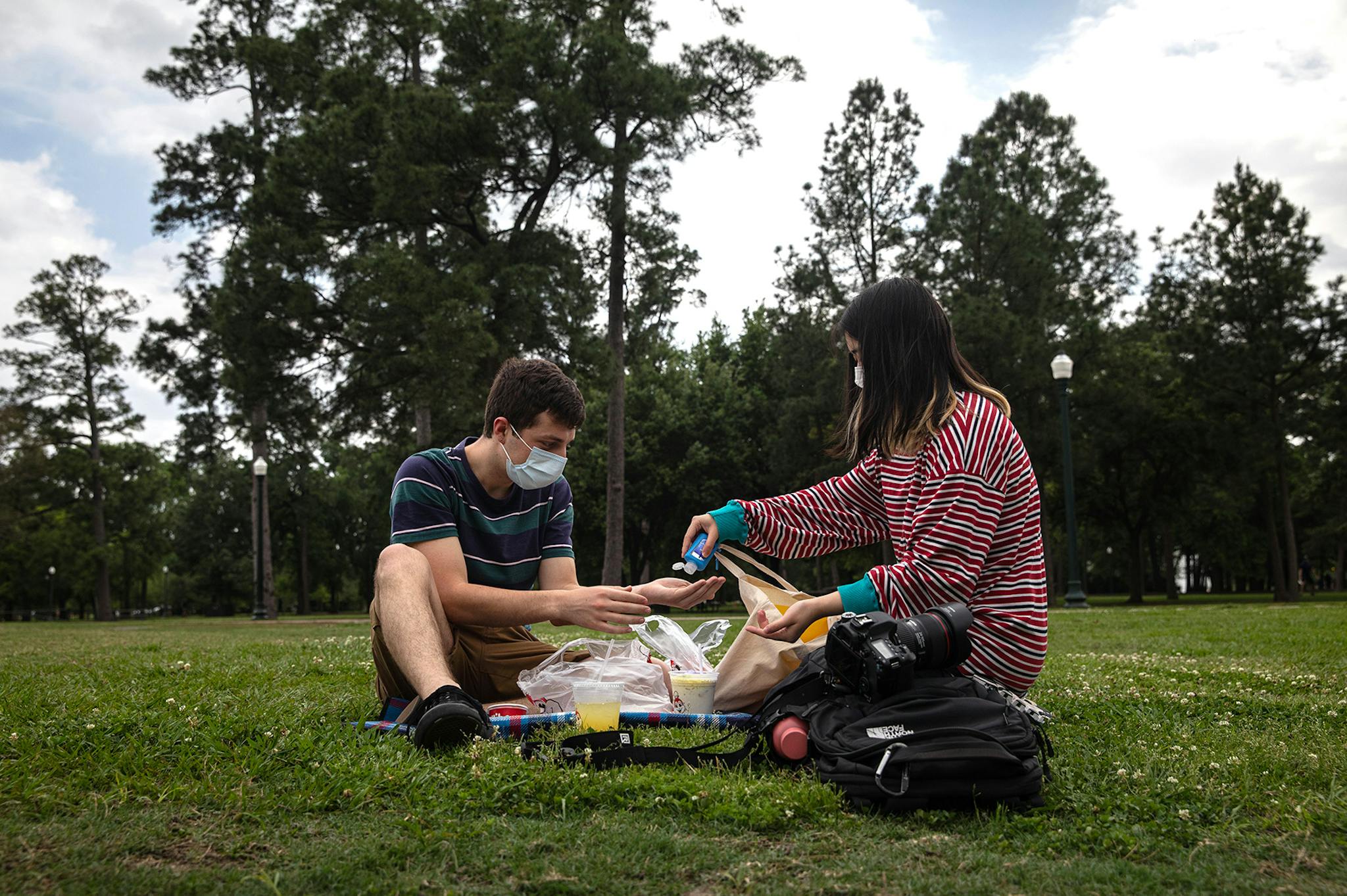 Sam Clegg and Jessy Dong share hand sanitizer at Houston’s Hermann Park.