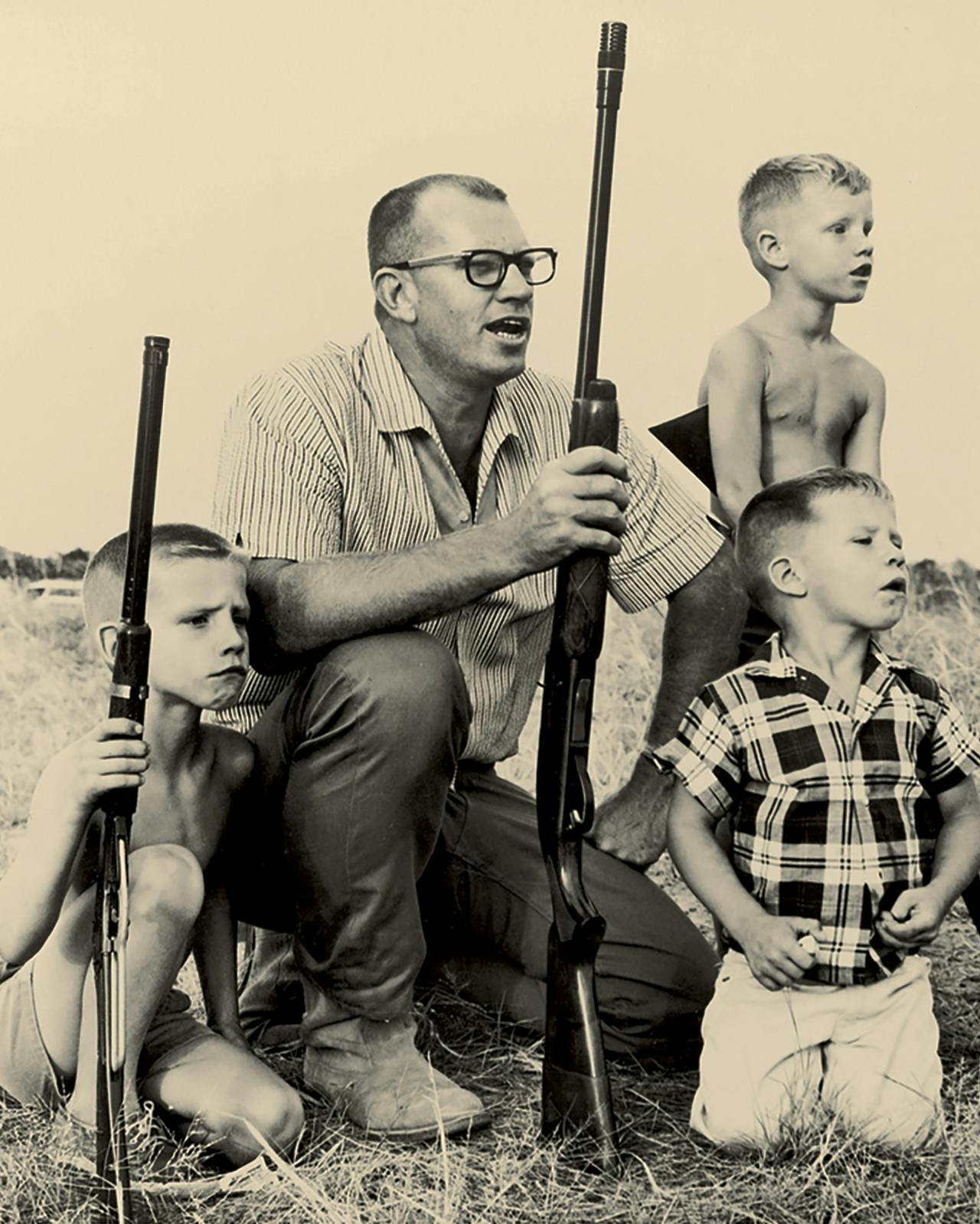 Old photograph of Kevin Von Erich with his dad and two of his brothers practicing shooting. 