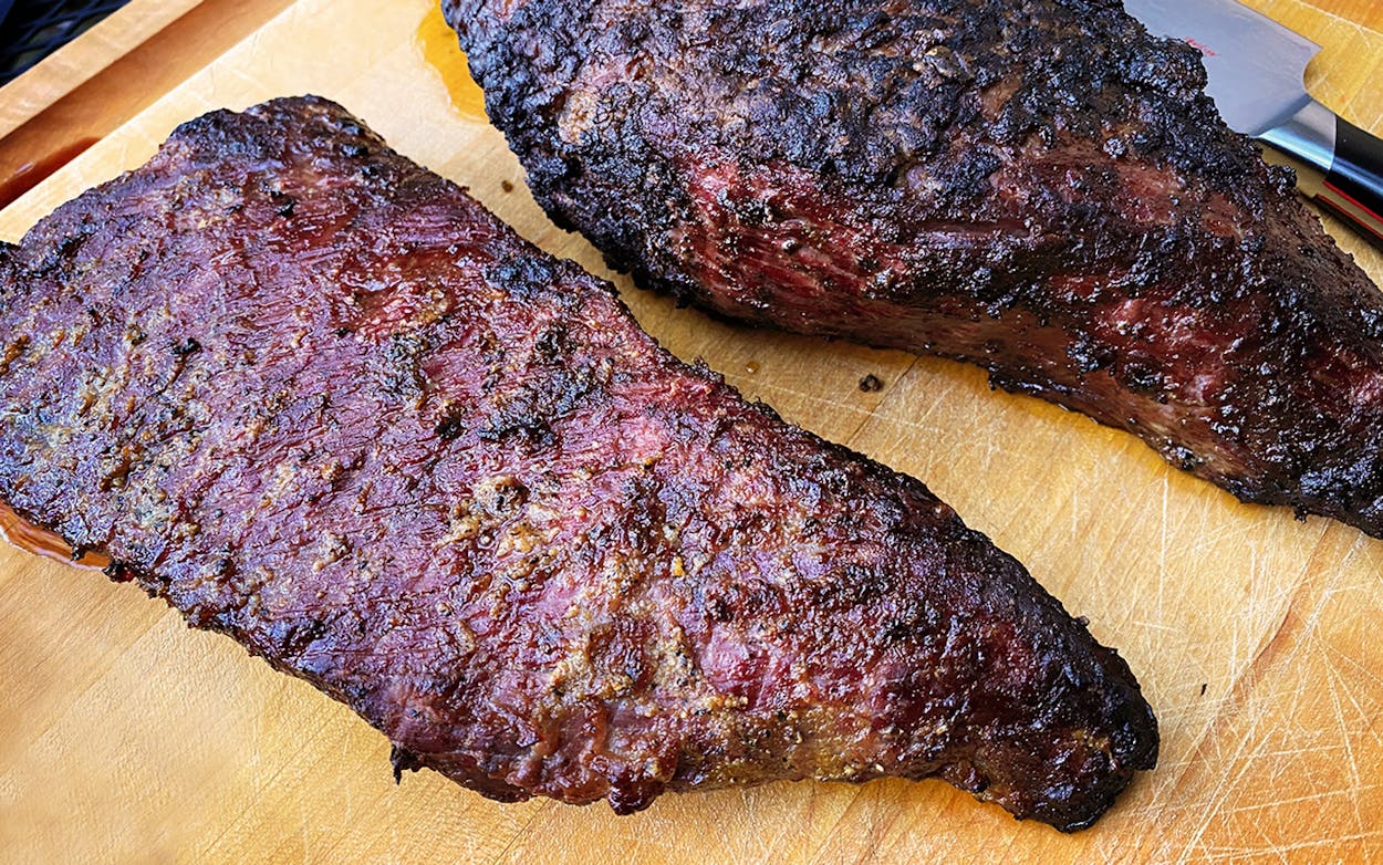 Two whole smoked tri-tips on a cutting board.