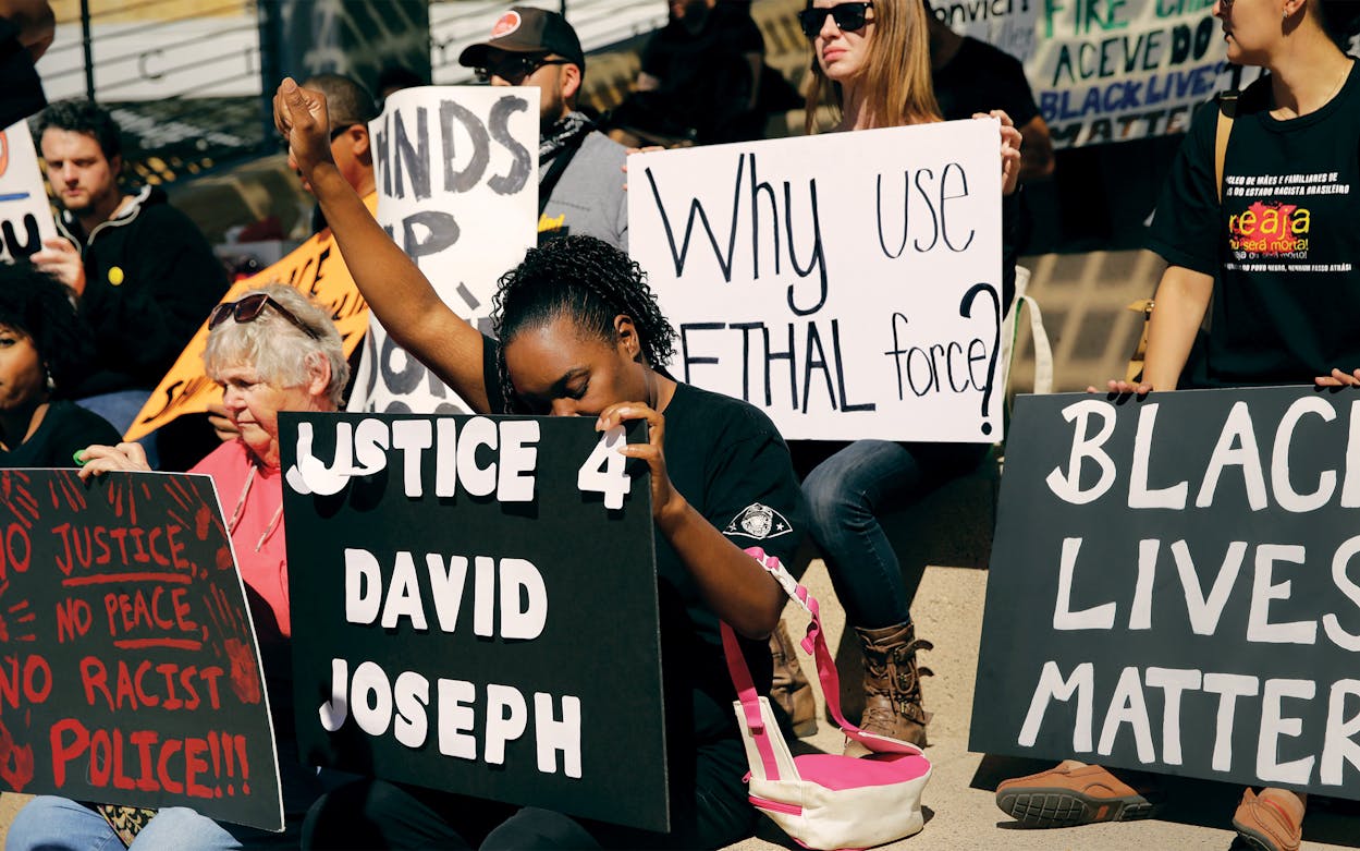 Juanita Spears, center, raises her hand during a rally at Austin City Hall in response to the recent fatal police shooting of David Joseph, 17, in Austin, on February 11, 2016. The shooting of Joseph, who was naked and unarmed, has provoked outcry among social justice activist groups.