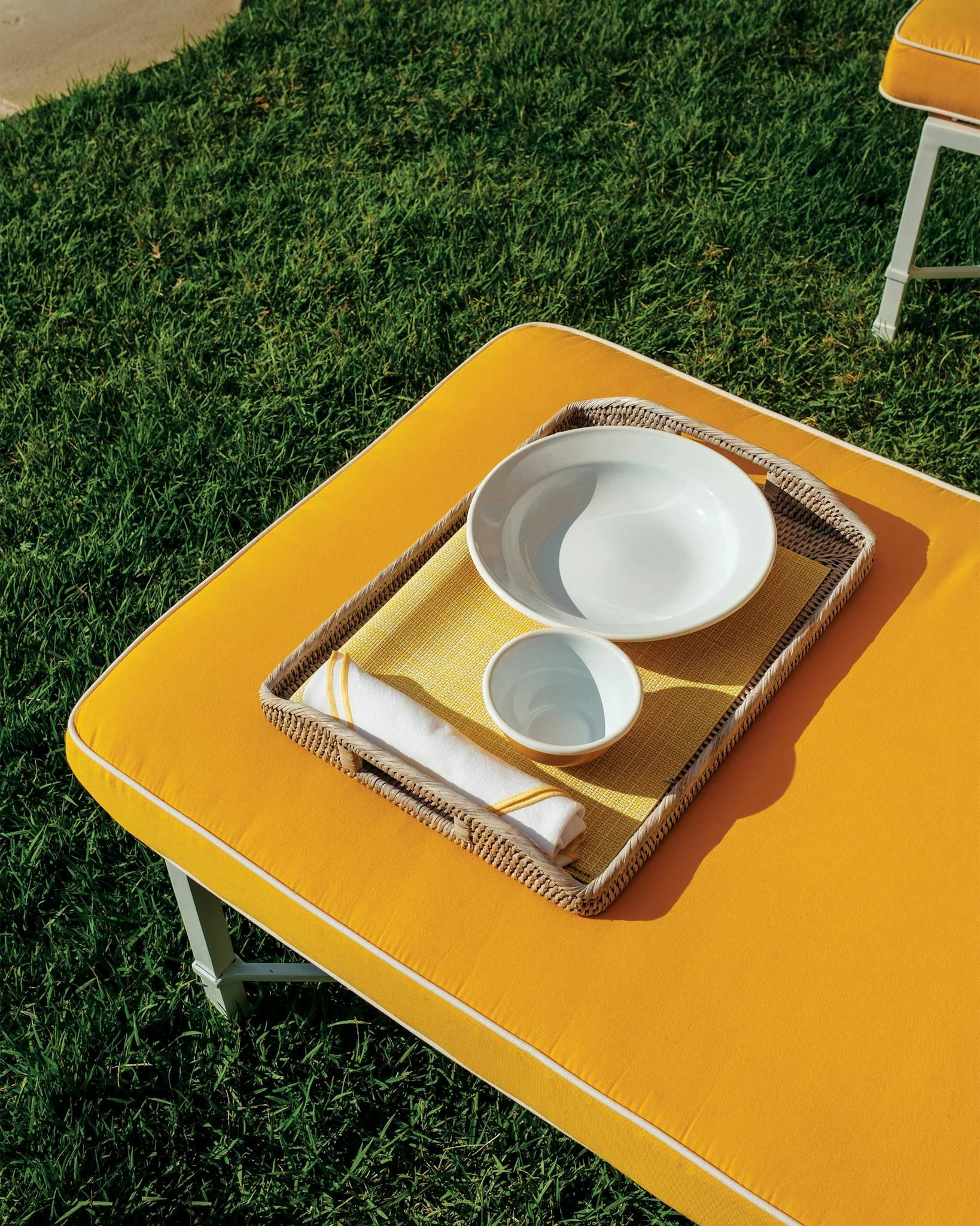 Tray with two dishes and silverware atop a yellow table.