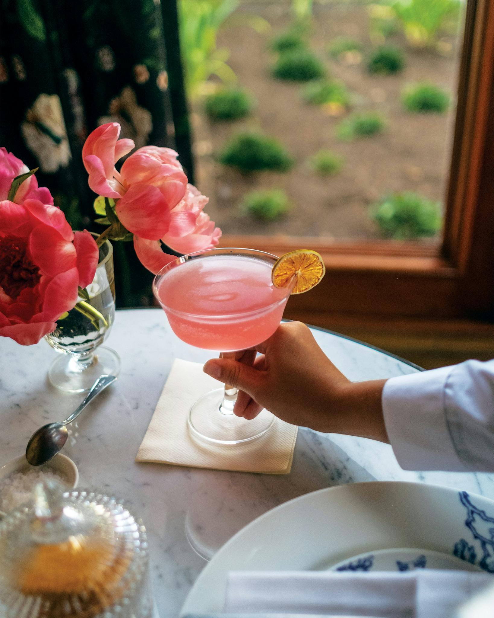 Pink cocktail garnished with a lemon.