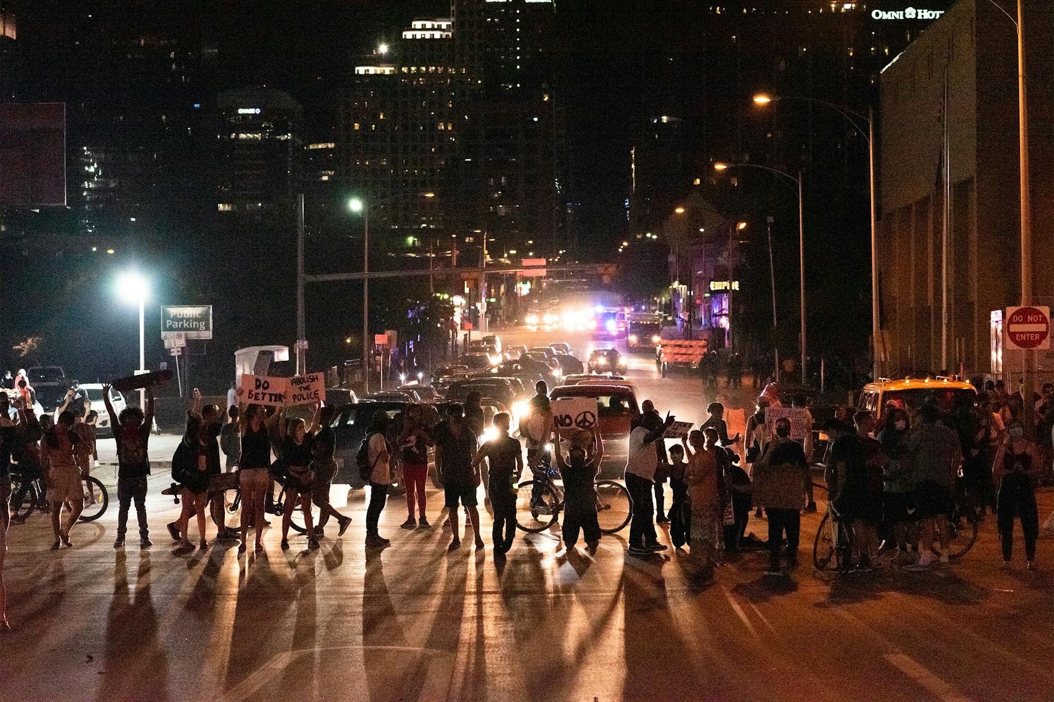 Protesters kneel while blocking the intersection of 7th Street and I-35 in front of police headquarters in Austin on May 30, 2020.