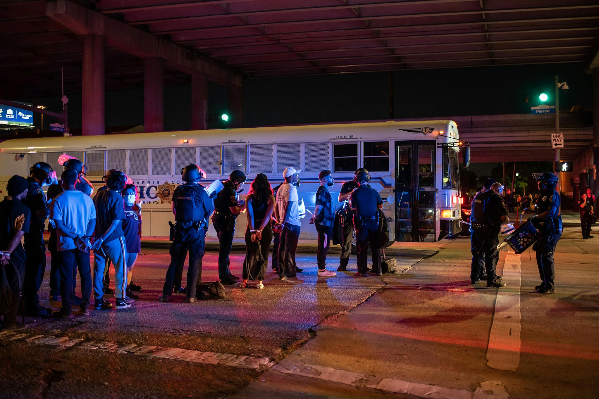 A group of people being placed under arrest stand by a Harris County Jail bus after protesters were apprehended in a fenced in area in Houston, on June 2, 2020.