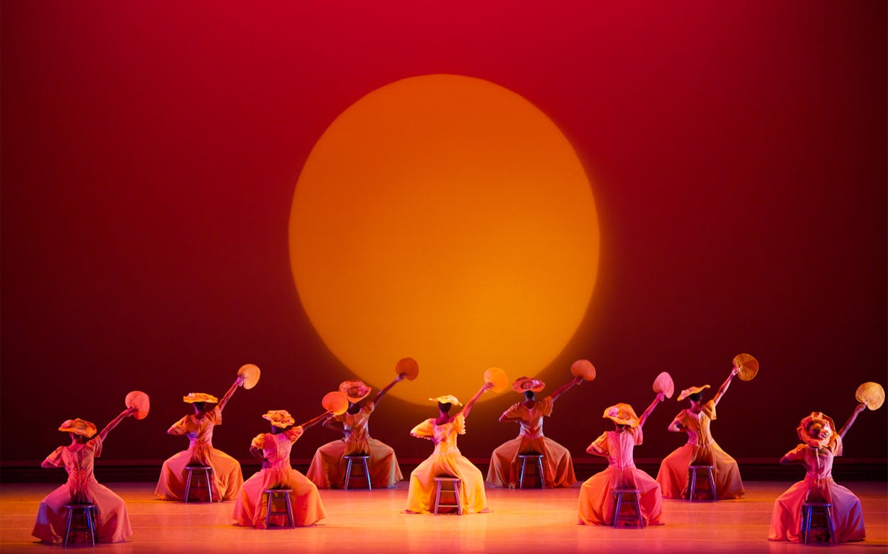 Alvin Ailey dancers performing on an orange-lit stage.