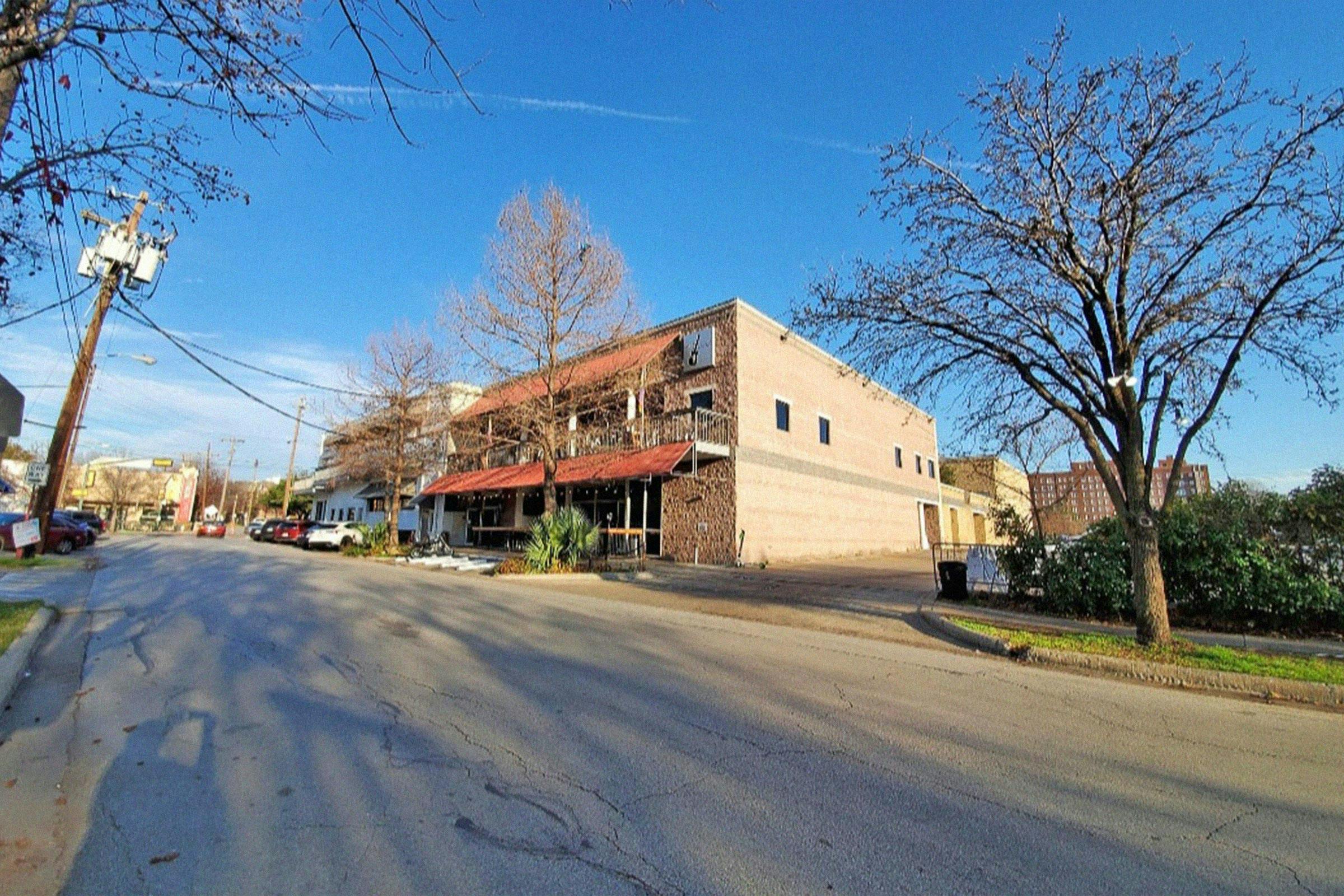 Street view of Sue Ellen's night club with brick exterior and red awnings. 