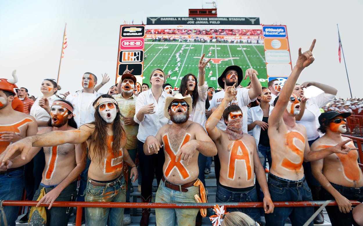 UT students at a football game with their chests painted to spell 