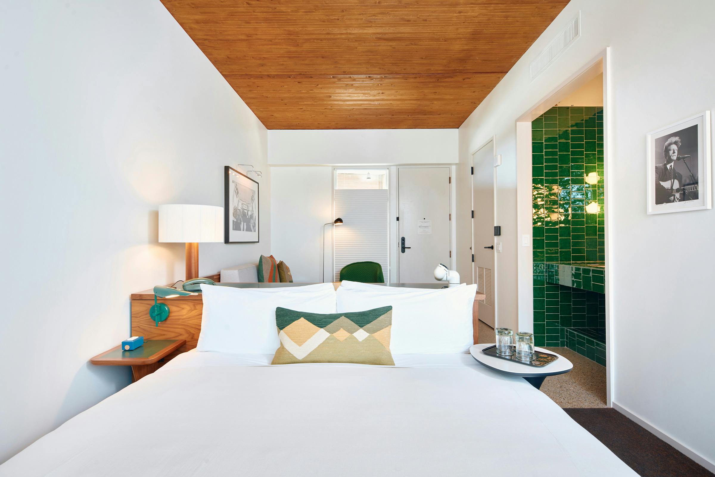 One of Hotel Magdalena's guest rooms, showing a crisply made bed and a deep green tiled counter. 