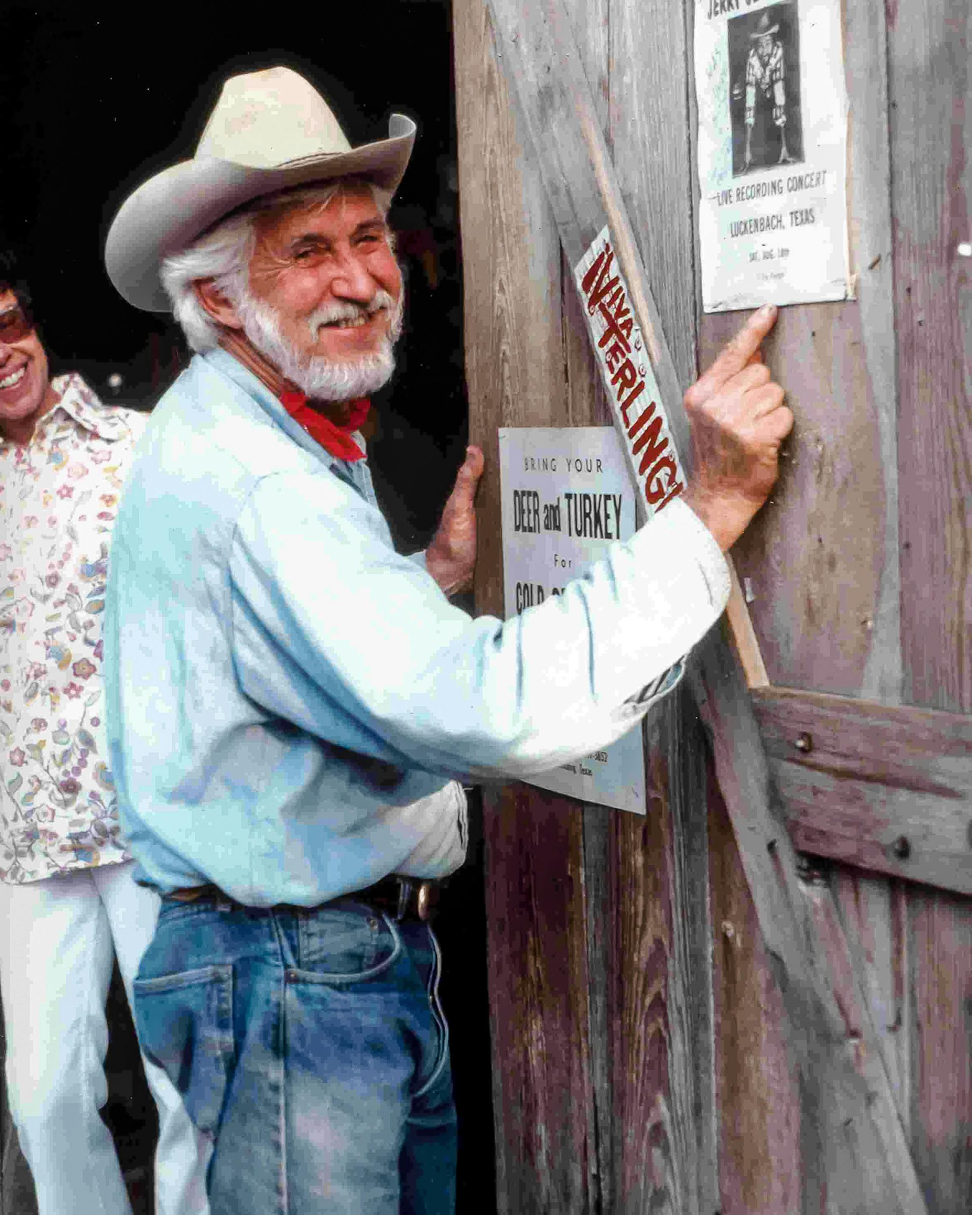 Hondo Crouch pointing to a poster tacked up on a wooden door. 