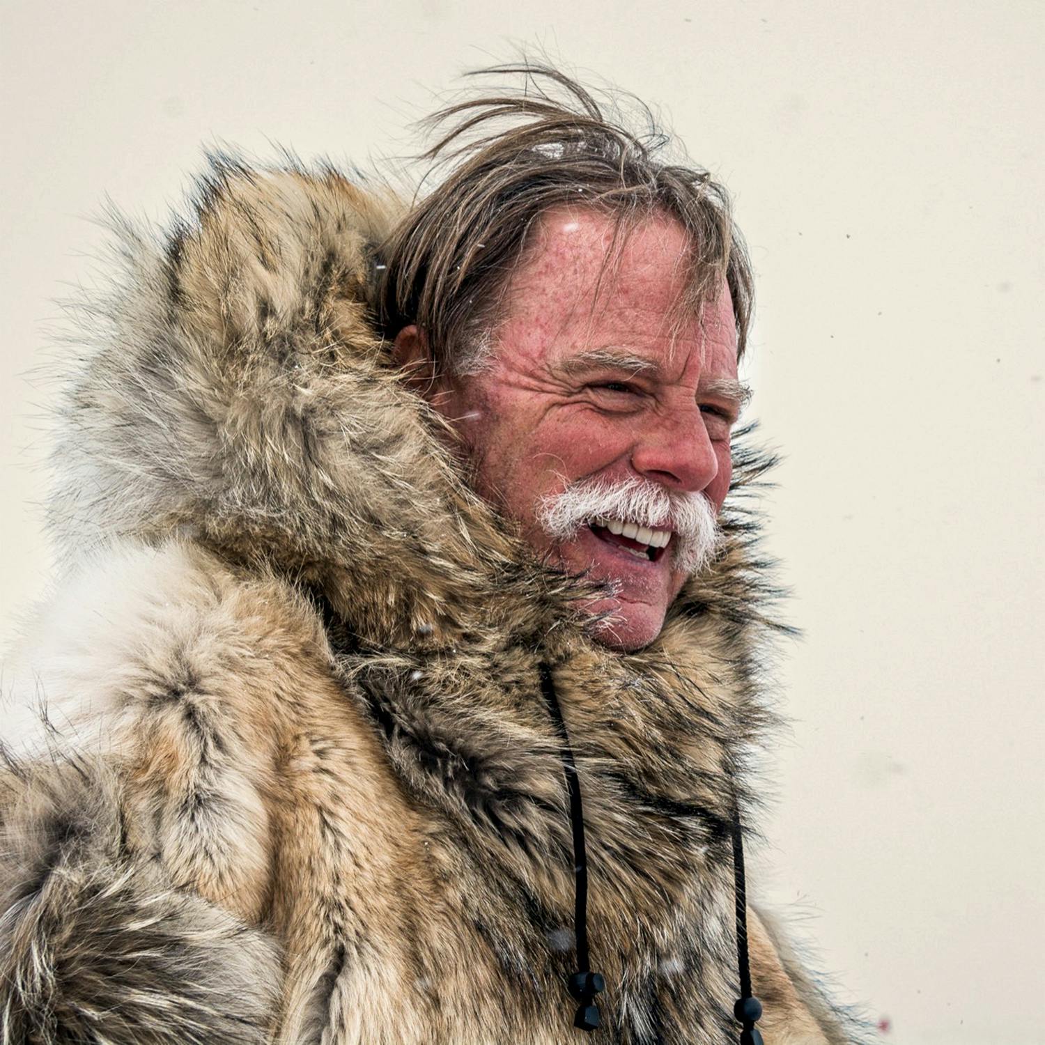 Wayne White, laughing in a fur parka with the hood down. 
