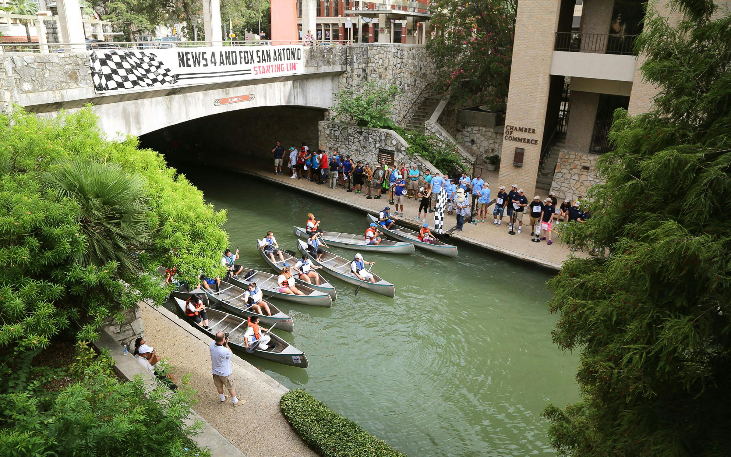 Seven two-seater canoes lined up in the San Antonio River. 