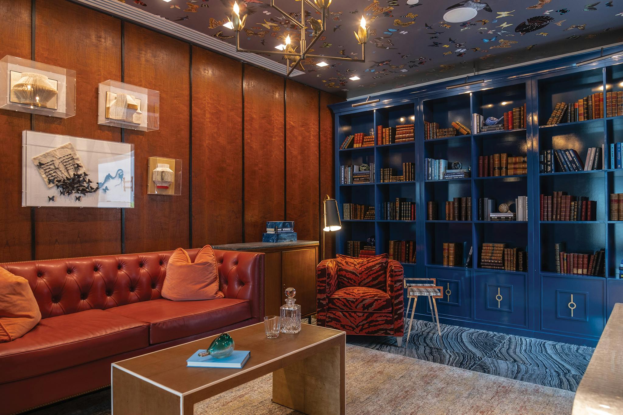 The Thompson Hotel's library lounge with a brown leather couch and full bookcase.