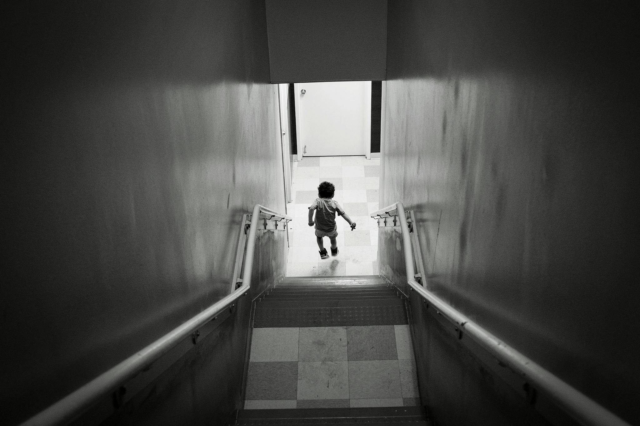 A young boy jumps down a stairwell on the way to the shelter’s cafeteria after lunch is announced over the intercom.