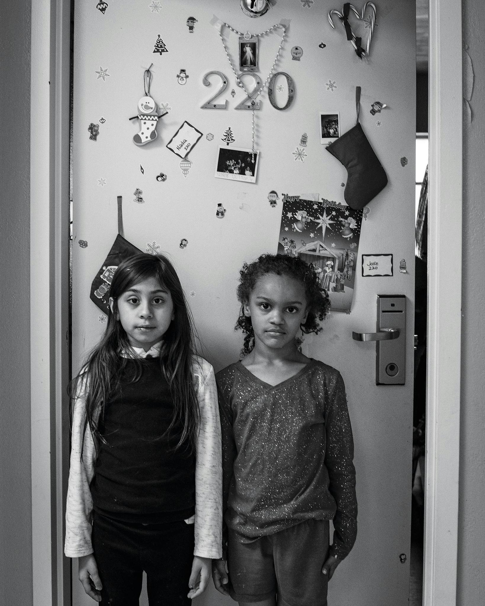 Nadia De La Torre, 9, stands outside her family’s room with her friend Skye Griffin, 8, who lives next door.