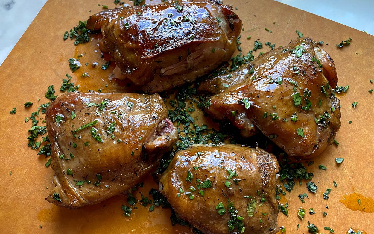 four confit chicken thighs arranged on a plate