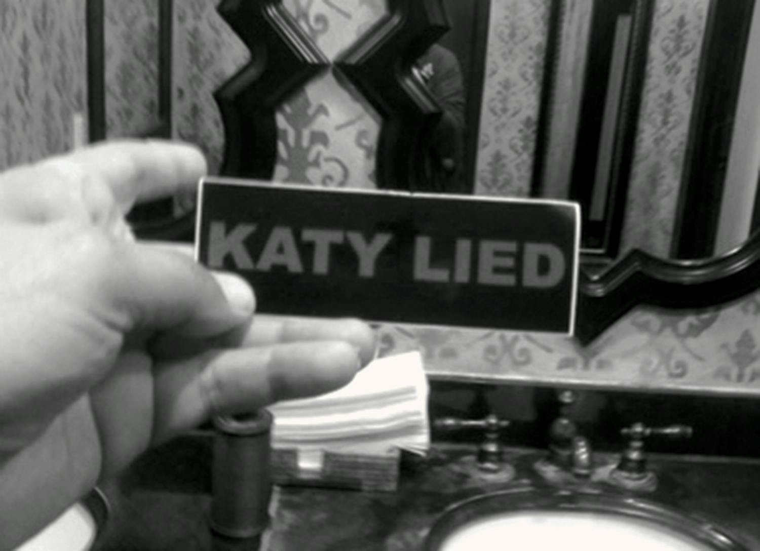 Sticker reading, "Katy Lied," photographed in a public bathroom. 
