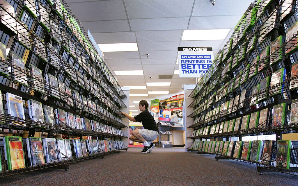 Blockbuster manager crouches to organize the DVDs. 