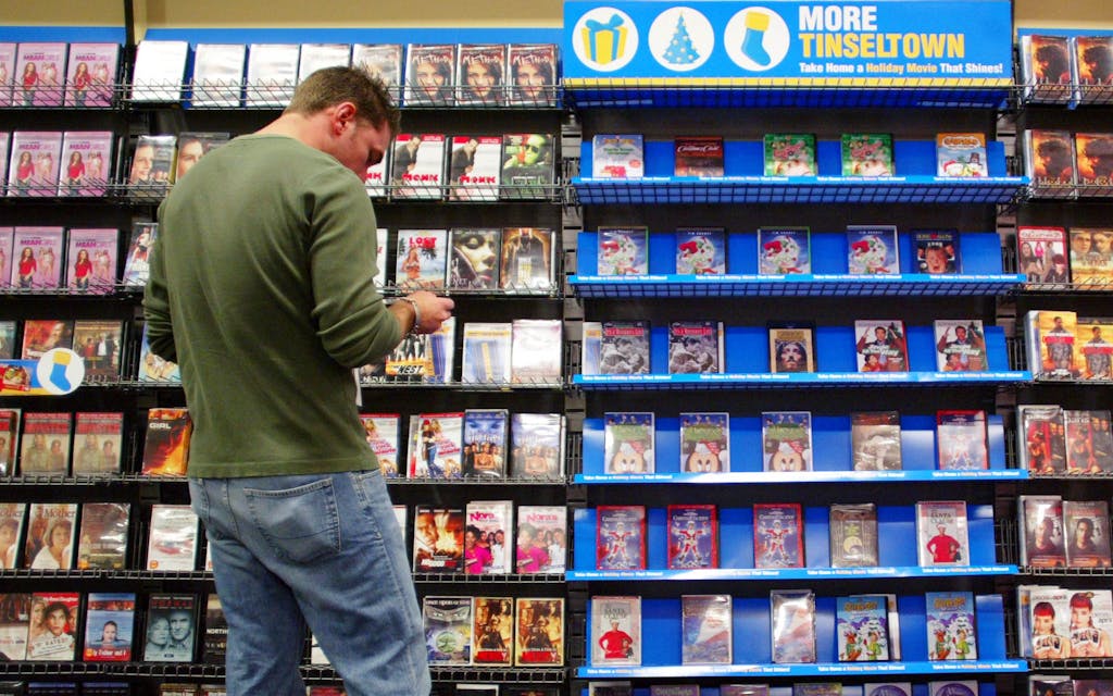 Customer choosing from shelves of DVDs. 