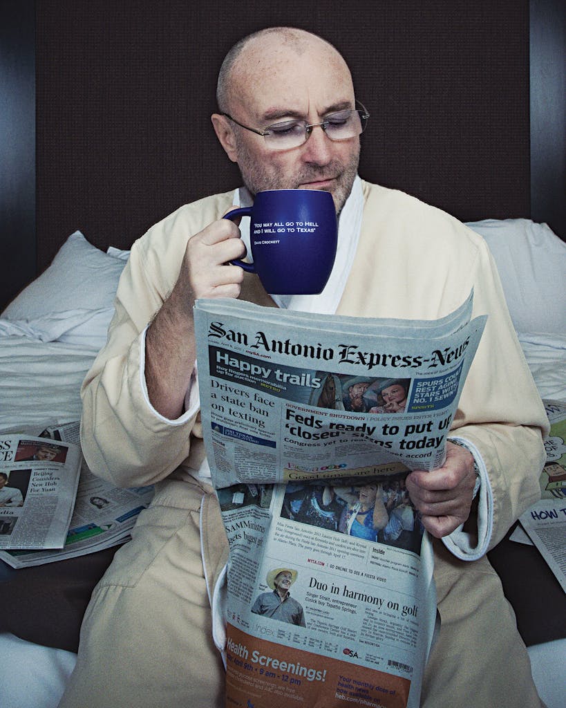 Phil Collins reading the newspaper with a cup of coffee. 