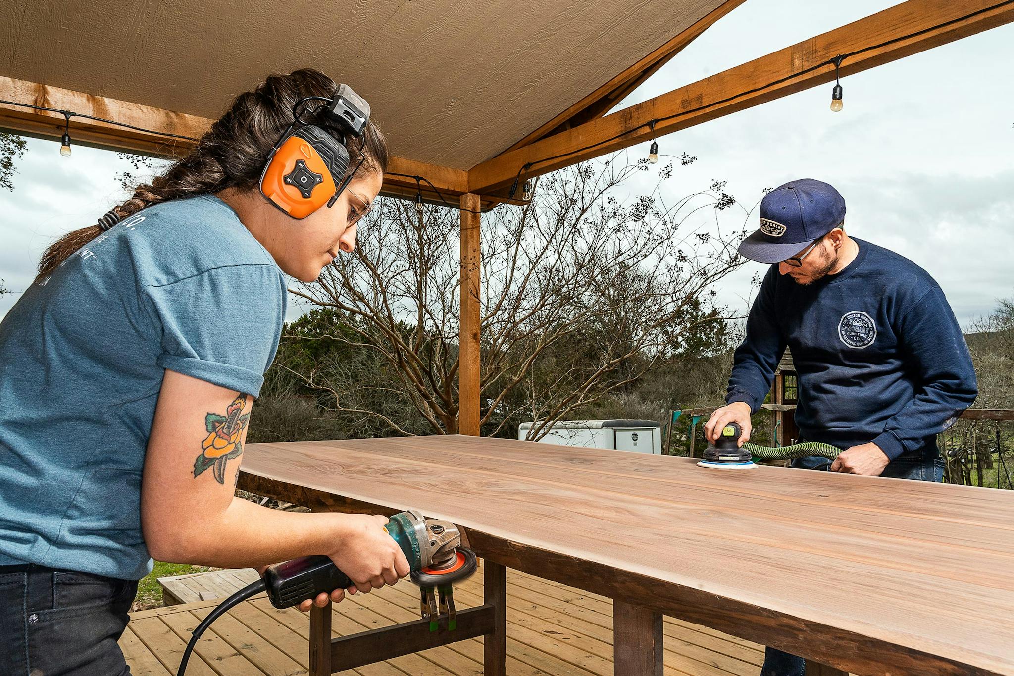 Morley (right) and his apprentice Amanda Russell sand down a book-matched live edge walnut table top at his studio in Wimberly on March 8, 2021.