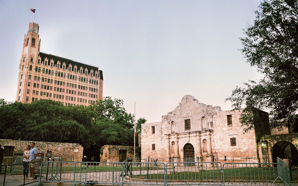 Two people posing in front of the Alamo. 
