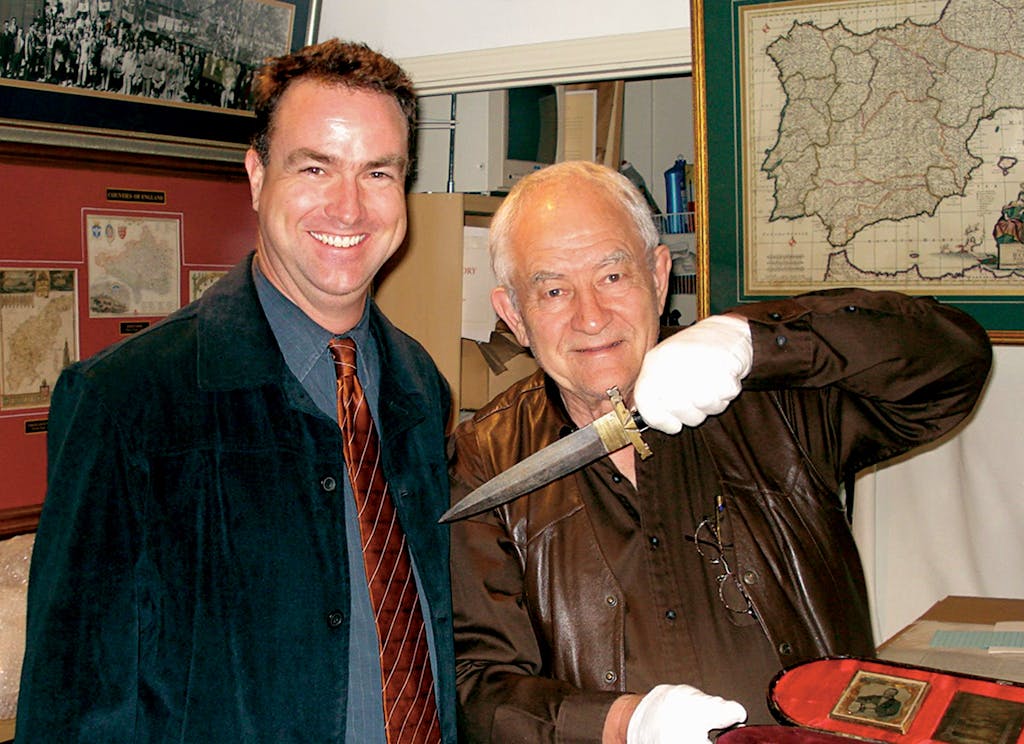 Jim Guimarinholding a dagger, next to a smiling customer. 