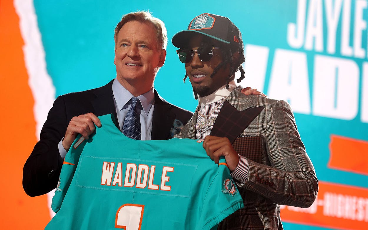 Jaylen Waddle poses with NFL Commissioner Roger Goodell onstage after being selected with the sixth pick by the Miami Dolphins during round one of the 2021 NFL Draft at the Great Lakes Science Center on April 29, 2021 in Cleveland, Ohio.