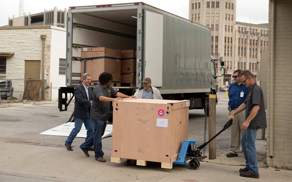 Five men moving big boxes to a moving truck. 