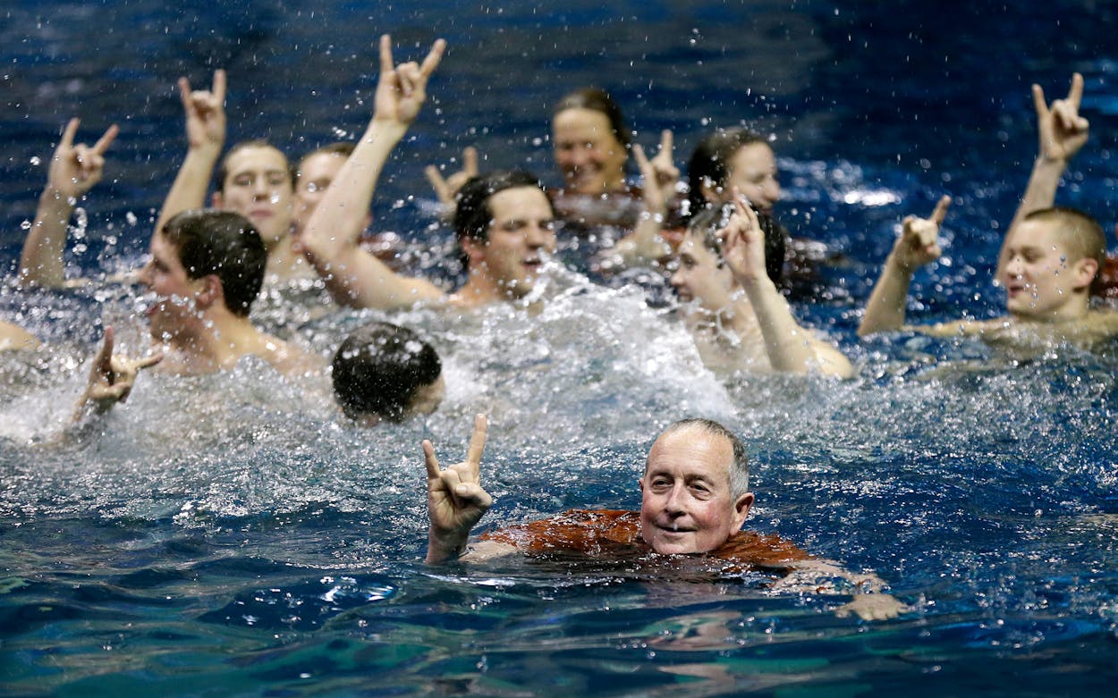 Texas head coach Eddie Reese celebrates with his swimmers in the pool after winning the team title at the NCAA men's swimming and diving championships, Saturday, March 28, 2015, in Iowa City, Iowa.