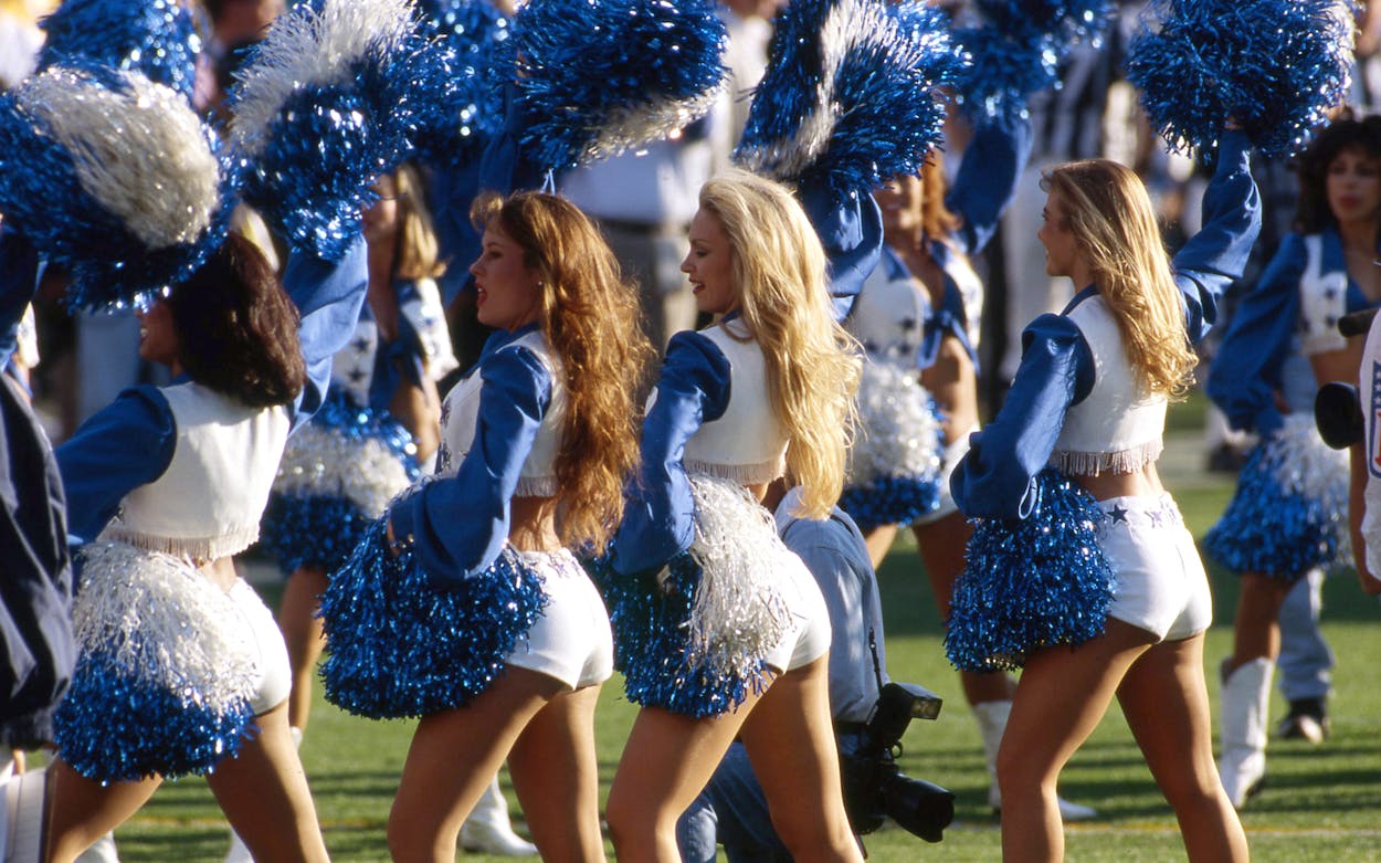 Dallas cowboy cheerleaders photographed while cheering from behind.