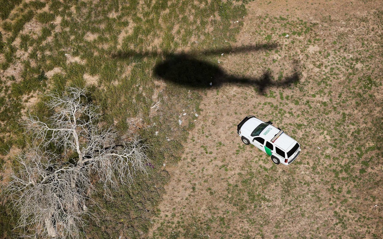 The shadow of a helicopter from U.S. Office of Air and Marine passes a U.S. Border Patrol vehicle as agents search for undocumented immigrants in 2014 in Falfurrias.