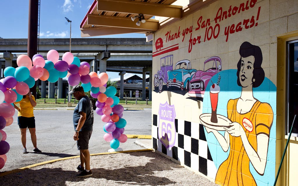 Volunteers set up a balloon arch outside a mural on the side of the Pig Stand.