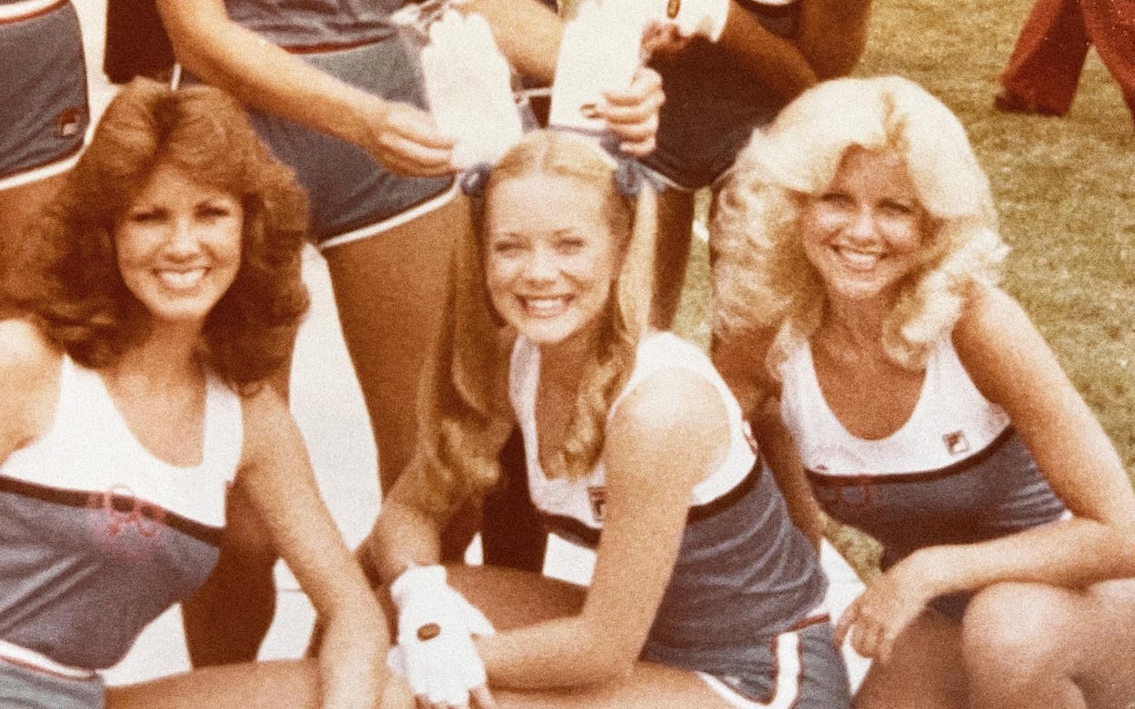 Dallas Cowboys Cheerleader sitting on the sidelines in their uniforms.