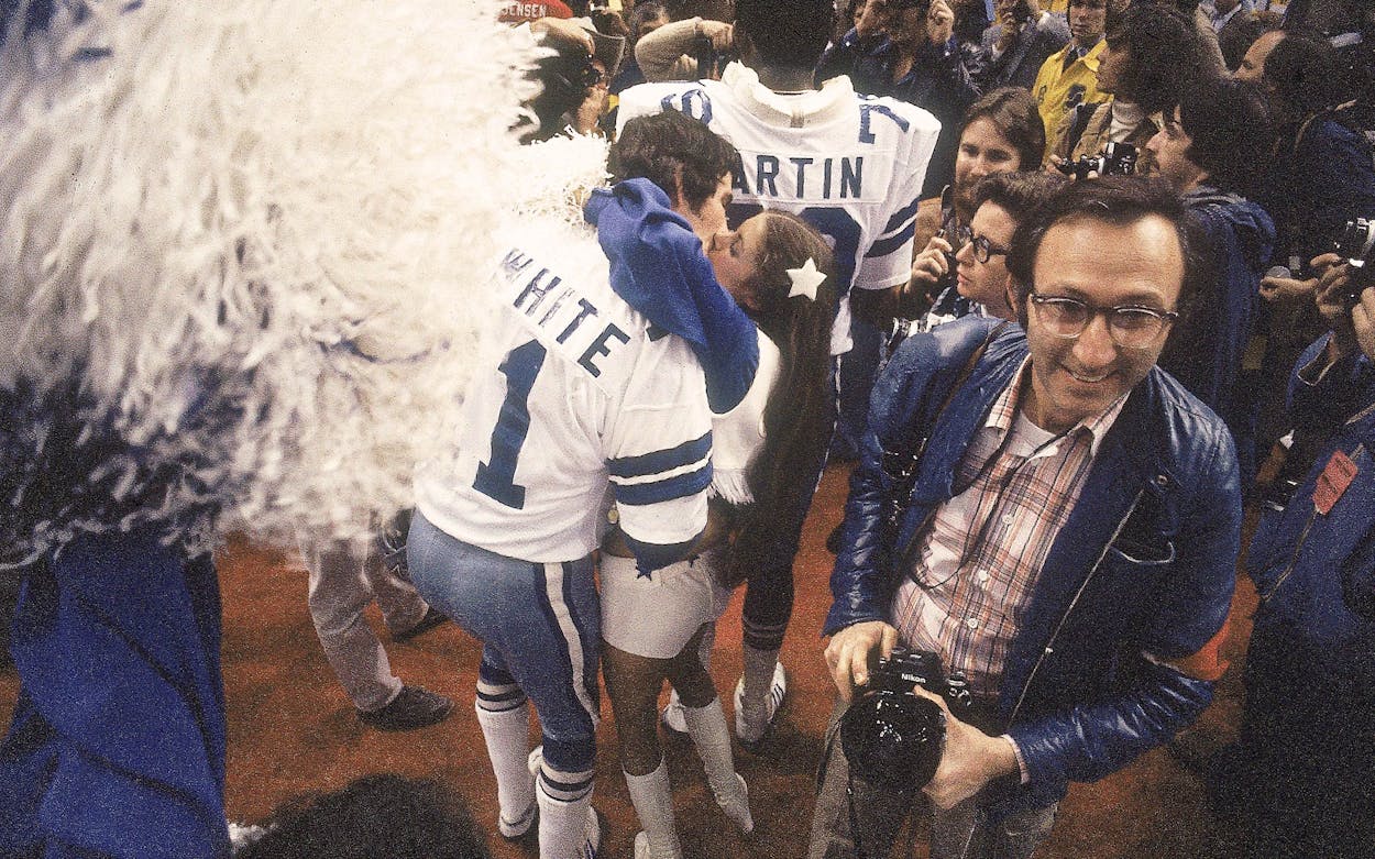 Dallas Cowboy quarter back Danny White victorious, kissing cheerleader after winning game.