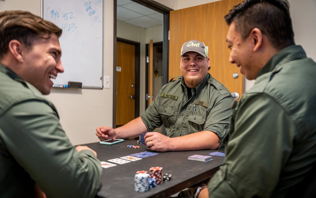 Dominic Sanchez, Steven Hutson, and Anthony Luk play poker in the clinic while waiting for a call.