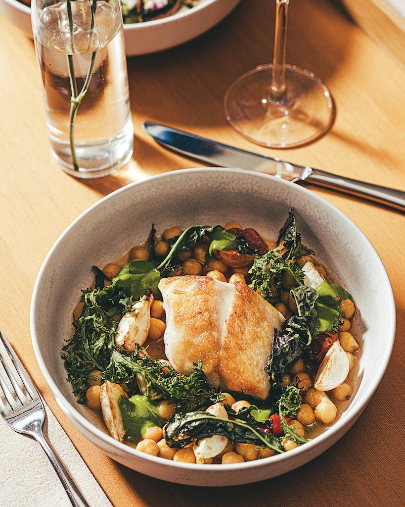 Rockfish filet served on a bed of braised chickpeas with turnips, mustard greens, and basil pistou at Birdie’s, in Austin, on December 10, 2021.