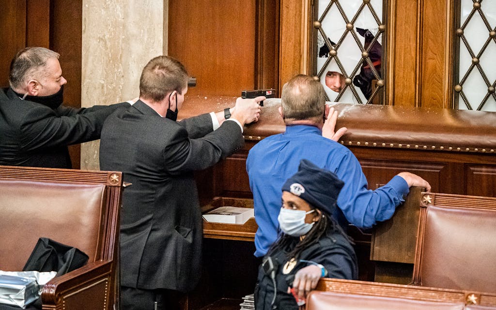 U.S. Capitol Police agents aim their guns as a pro-Trump mob tries to break into the House of Representatives chamber at the Capitol in Washington on Jan. 6, 2021. Rep. Troy Nehls (R-TX) in blue shirt, talks to one of the rioters.