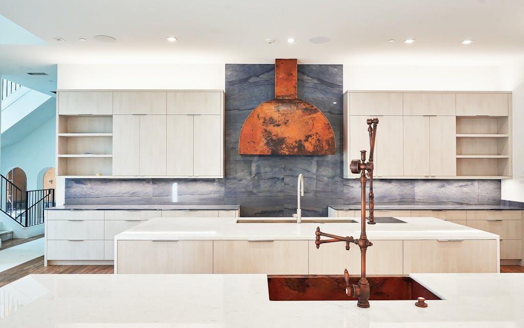 The kitchen, with two marble-topped islands and an Azul Macaubus stone backsplash on the cooktop wall. 