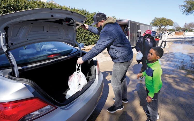 Pastor Jessie Prince and his son Josiah handing out water at their Plano church.