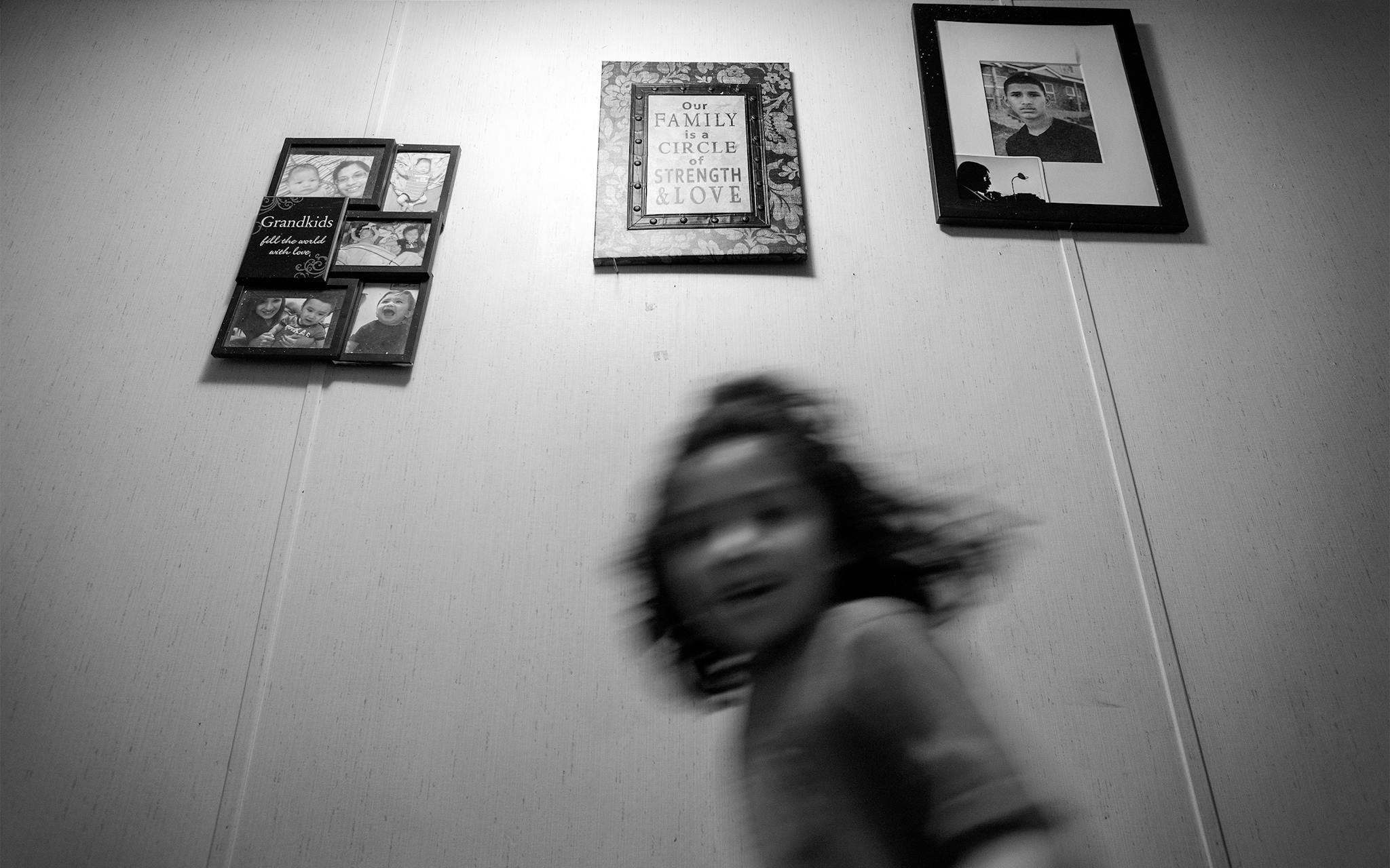 Arleen’s daughter Hailee runs past a photo of Christian in the hallway of Maricela’s home in Kyle on July 16, 2020.