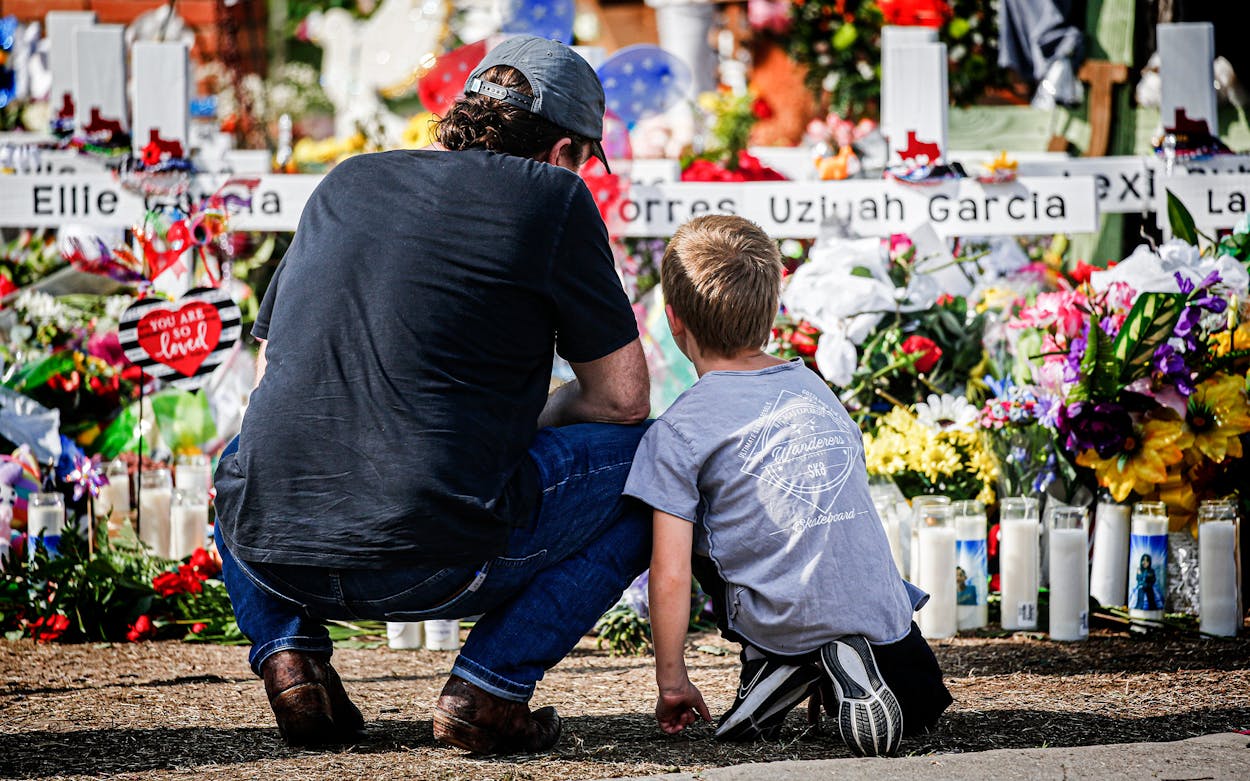 A man and a child pay their respects at a memorial outside Robb Elementary School to honor the victims killed in a school shooting in Uvalde on May 29, 2022.
