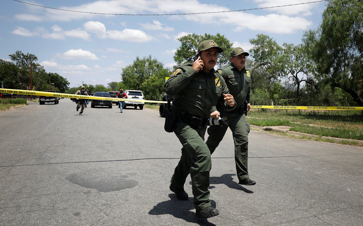 Law enforcement personnel run away from the scene of a suspected shooting near Robb Elementary School in Uvalde.