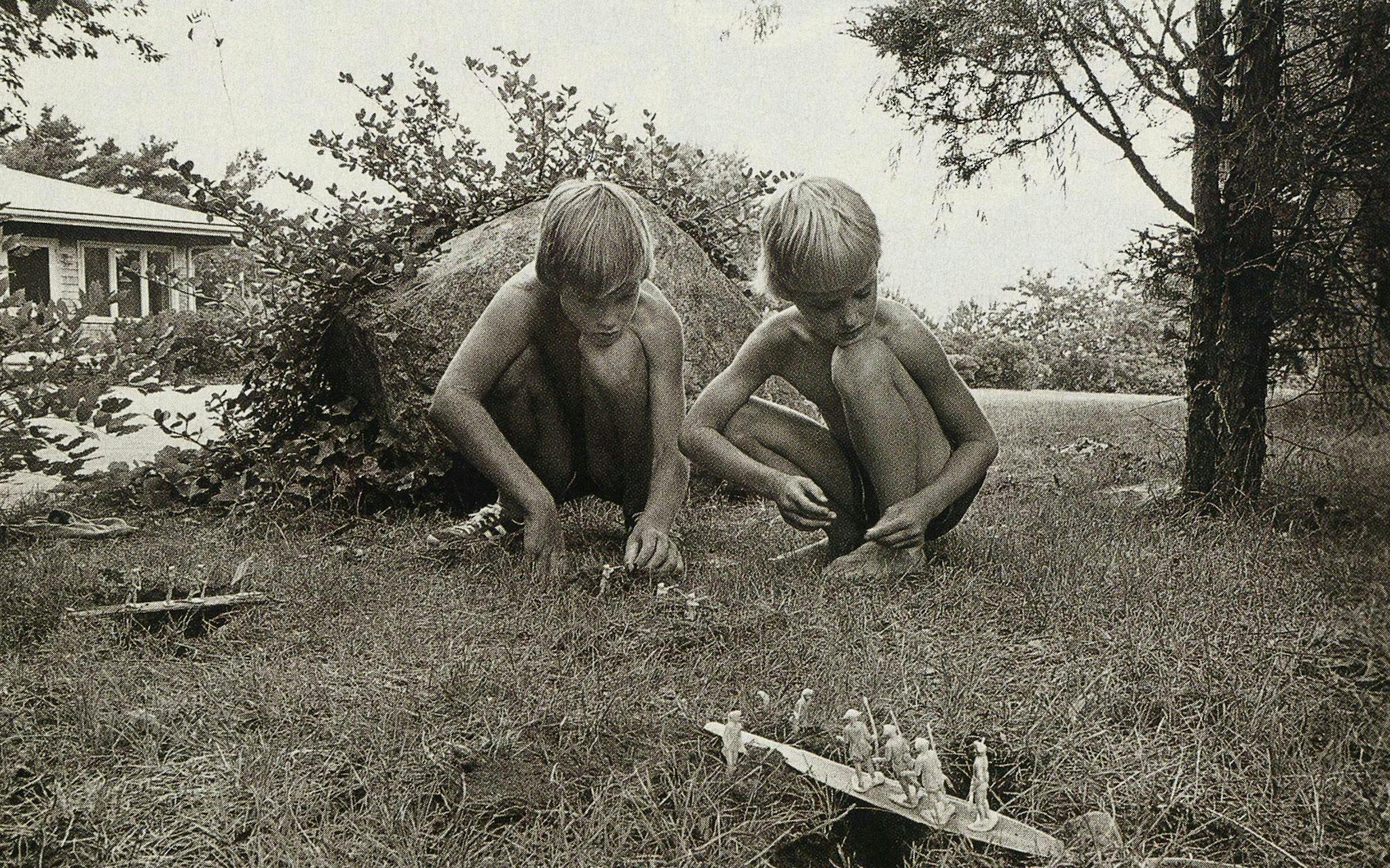 Young Andrew and Owen Wilson squatting over their game of toy soldiers.