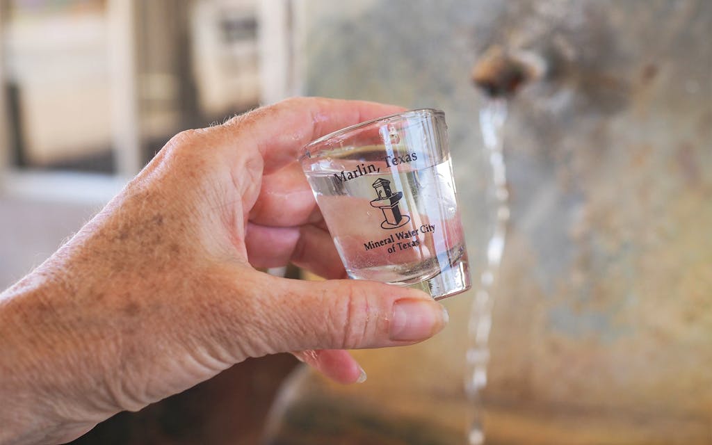 A shot glass of mineral water beneath the free-flowing spigot on Coleman Street, next to the Marlin Chamber of Commerce.