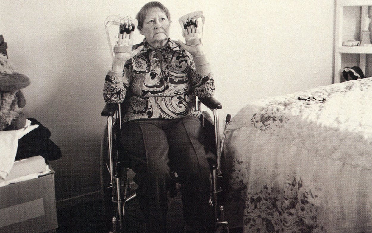 Leita Nobles, wheelchair bound, showing herfinger braces to the camera.
