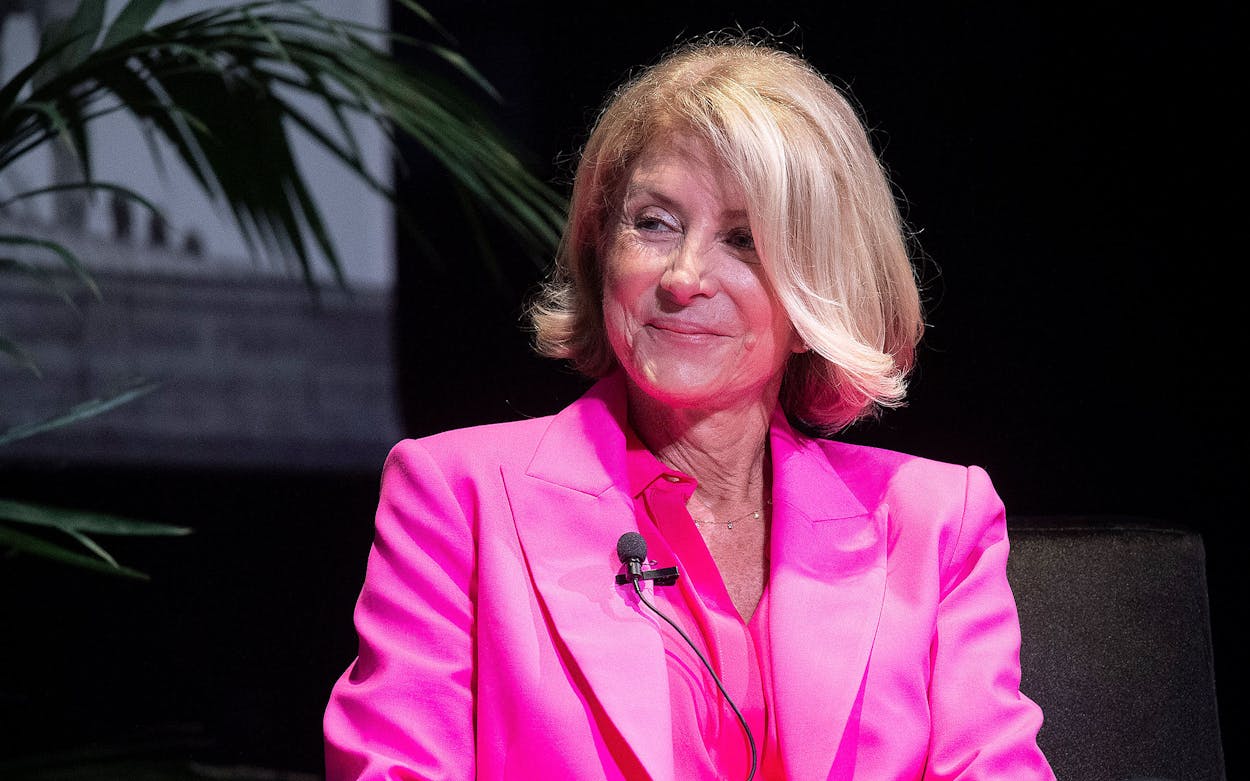 Wendy Davis wearing a pink suit with a microphone attached