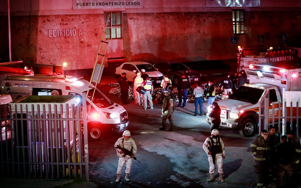 Paramedics and security forces work amid the covered bodies of migrants who died in a fire at an immigration detention center in Ciudad Juarez, Mexico, Tuesday, March 28, 2023.