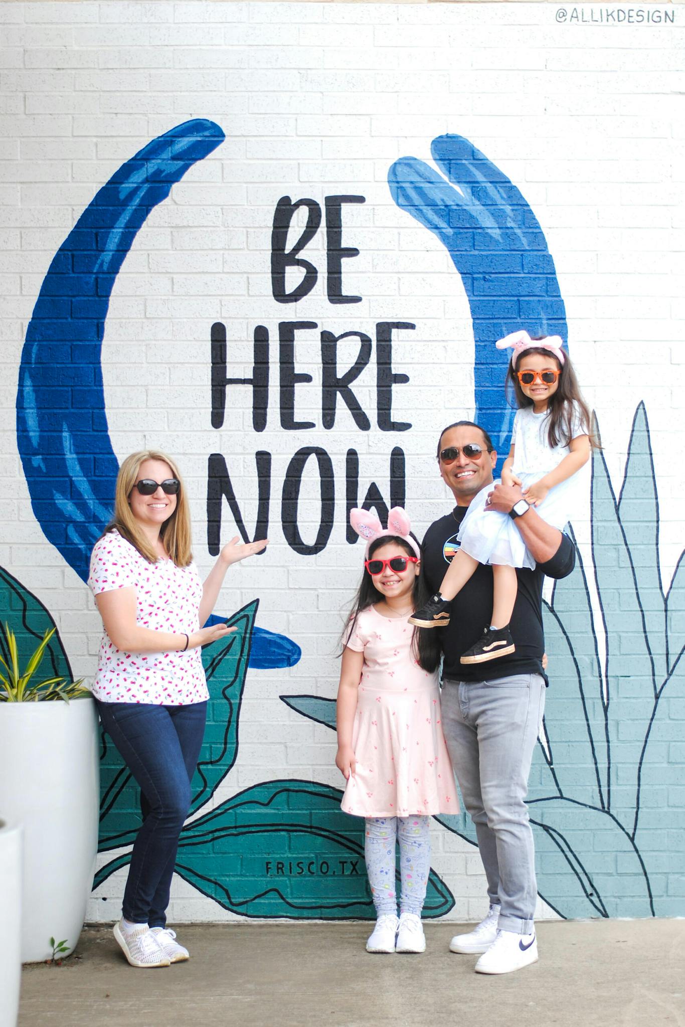 Family stands in front of a mural in Frisco, TX.