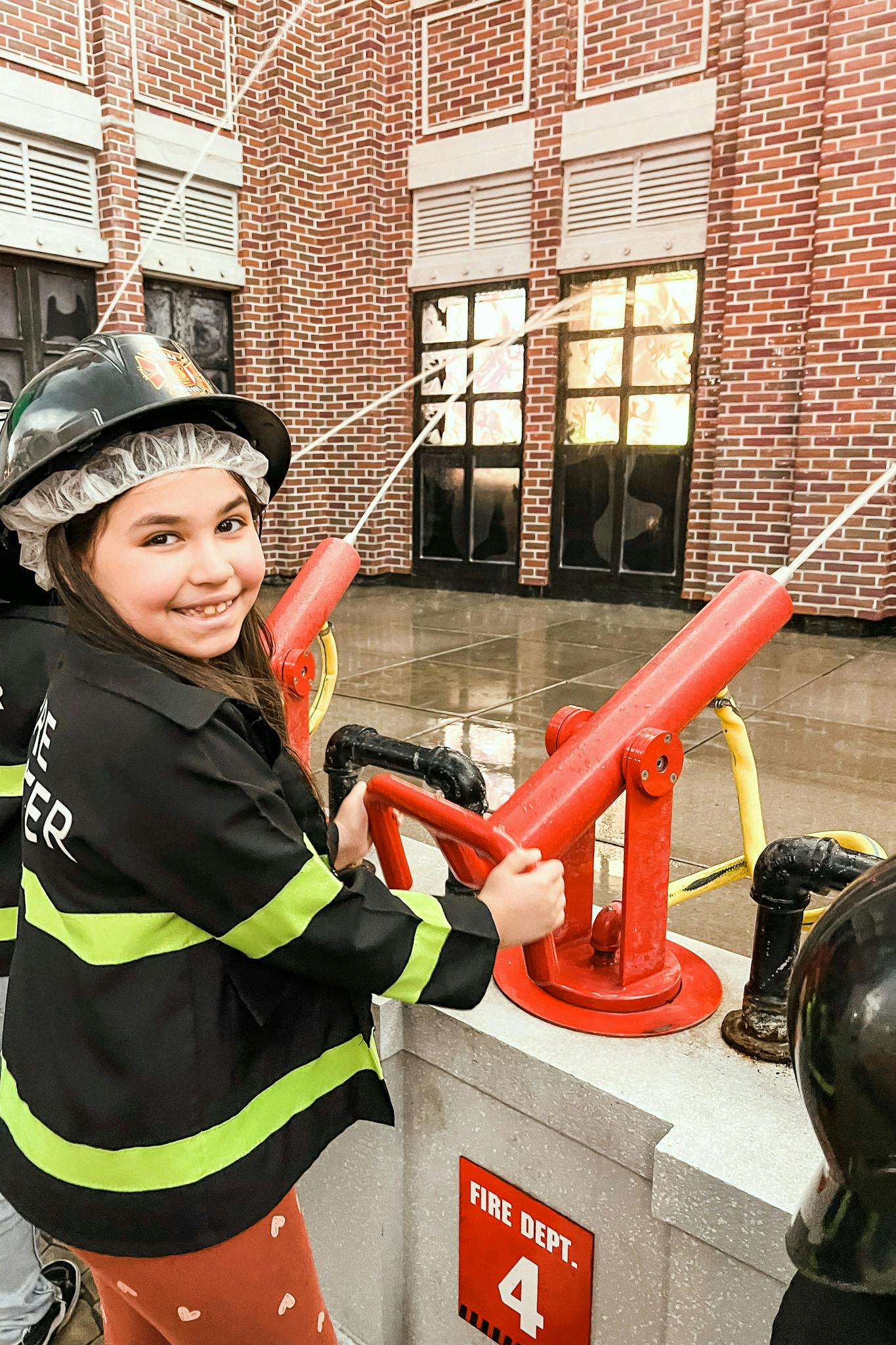 A little girl puts out a fire at a firefighting play exhibit at Kidzania.