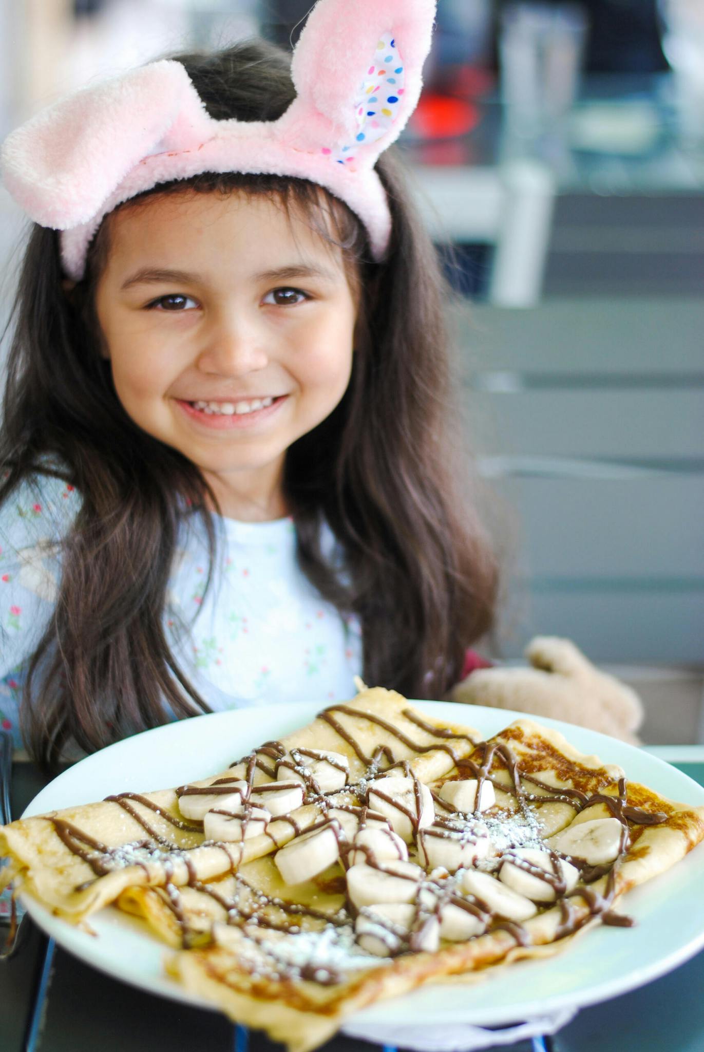 A little girl smiles showing off her pancake dish.